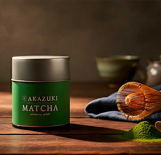 Green container of Akazuki Matcha on a wooden surface with tea-making tools.